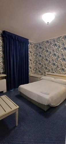 a bedroom with a large bed with blue curtains at BF SUITE Foresteria Bellusci in Rho