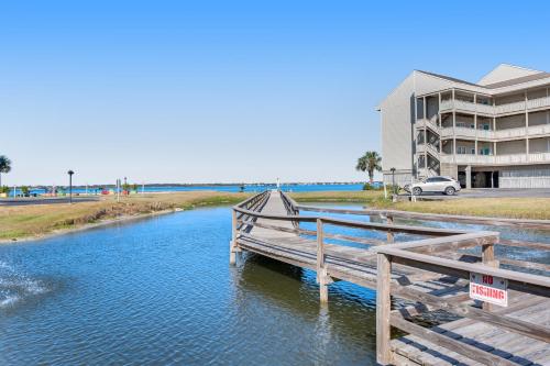 a wooden bridge over a river in front of a building at Condo with partial bay view onsite fishing dock beach access & shared pool in Pensacola Beach