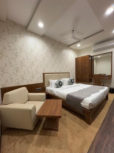 a bedroom with a bed and a couch and a table at Pam Premium Hotel Vadodara in Vadodara