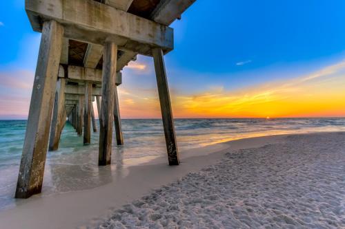 a pier on the beach at sunset at Dog-friendly duplex 2 blocks from beach with private yard AC & W&D in Panama City Beach