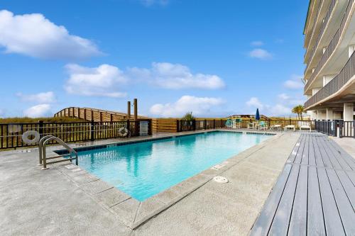 a swimming pool with a bench next to a building at Beachfront condo shared pool large balcony and beach access in Navarre