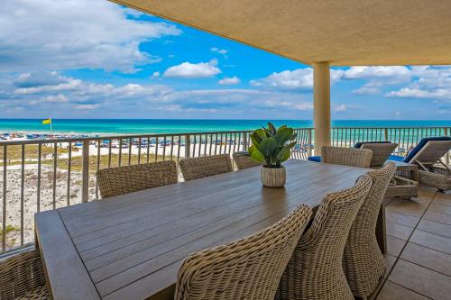 a wooden table with chairs on a balcony with the beach at Stunning beachfront condo with shared pool & beach access in Santa Rosa Beach