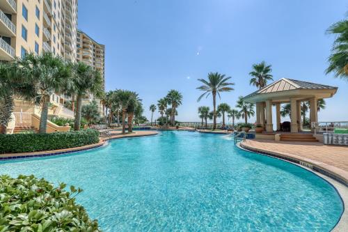 a swimming pool with palm trees and a gazebo at Gorgeous cozy beachfront condo with pool pool spa & beach access in Perdido Key
