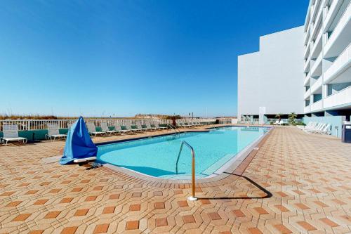 a swimming pool with a blue umbrella next to a building at Beautiful beachfront condo with shared pool & beach access in Fort Walton Beach