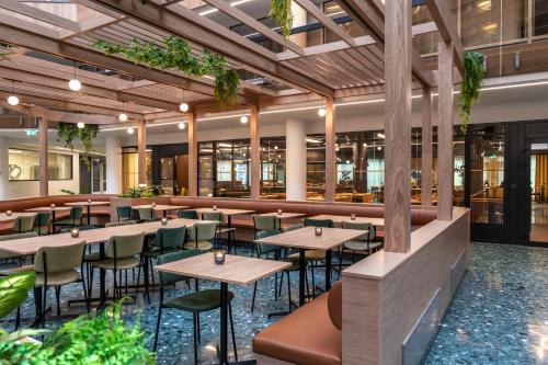 a restaurant with tables and chairs and plants at Thon Hotel Vika Atrium in Oslo