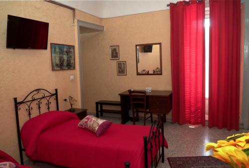 a bedroom with a bed and a desk and red curtains at B&B L'Angelica in Piazza Armerina