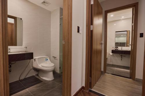 a bathroom with a toilet and a sink and a mirror at HongHome Happy One Central in Ga Phú Văn