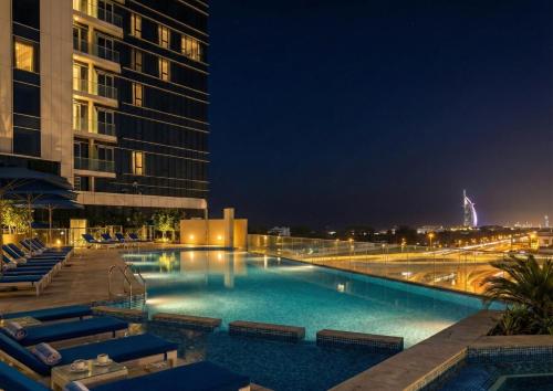 a large swimming pool at night with buildings at Ultimate Stay - Avani Palm Burj-AlArab View from the pool in Dubai