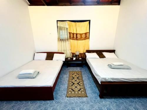 two twin beds in a room with a window at Village Breeze Villa in Haputale