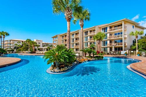 a swimming pool with palm trees in front of a building at Conveniently located Gulf condo with spacious layout pool & pickleball in Seacrest