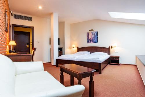 a hotel room with two beds and a couch at Wellness Hotel Gondola in Pilsen