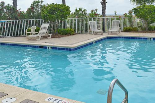 a swimming pool with two chairs and a fence at 3rd Floor Spacious Condo Close To Entertainment Shared pool Wifi in Navarre