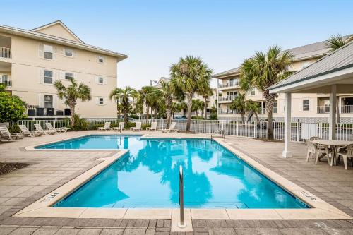 a swimming pool with a table and chairs next to a building at Spacious Condo with Balcony in Navarre Beach with Shared Pool in Navarre