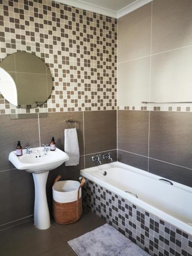 a bathroom with a sink and a tub and a mirror at Ocean Sands Accommodation in Richards Bay