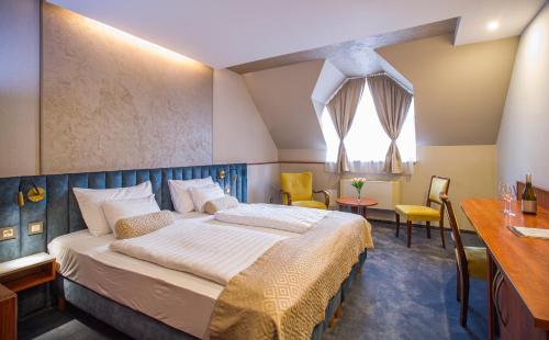 a bedroom with a bed and a table and chairs at Hotel Gottwald in Tata