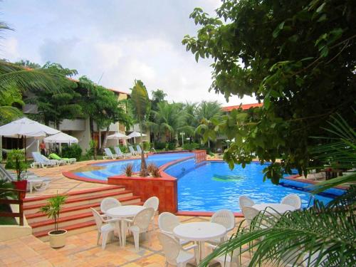 a pool at a resort with tables and chairs at Chalet Solar Pipa in Pipa