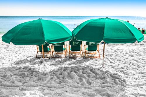 a group of chairs and umbrellas on a beach at Spacious 3rd-floor beachfront condo with stunning views pool pickleball & AC in Fort Walton Beach