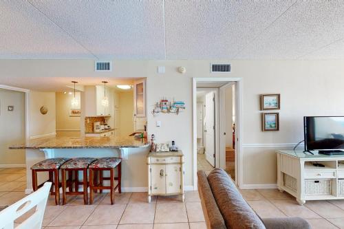 a living room with a kitchen and a bar with stools at Comfortable 6th-floor beachfront condo with ocean views - walkable locale in Fort Walton Beach