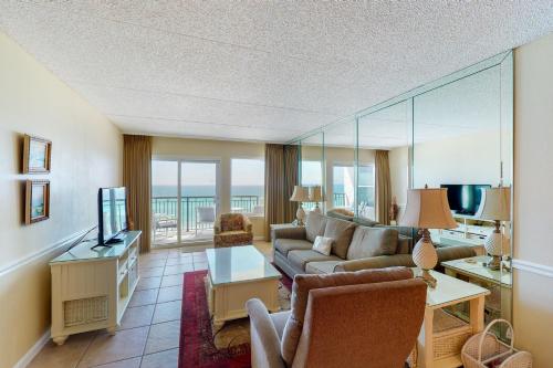 a living room with a couch and a television at Comfortable 6th-floor beachfront condo with ocean views - walkable locale in Fort Walton Beach