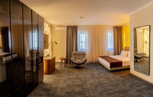 a hotel room with a bed and a chair at Infinity Plaza Hotel Block 1 in Atyrau