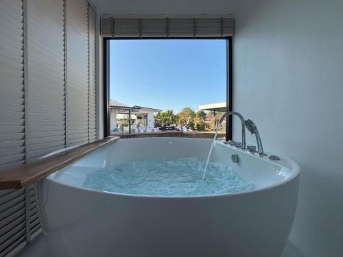 a bath tub in a room with a large window at Baan mae resort in Ban Takat Ngao