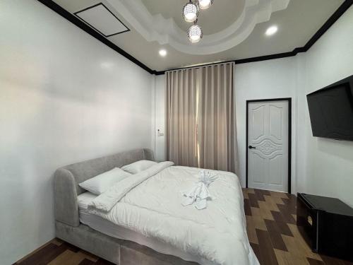 a bedroom with a bed with white sheets and a television at Baan mae resort in Ban Takat Ngao