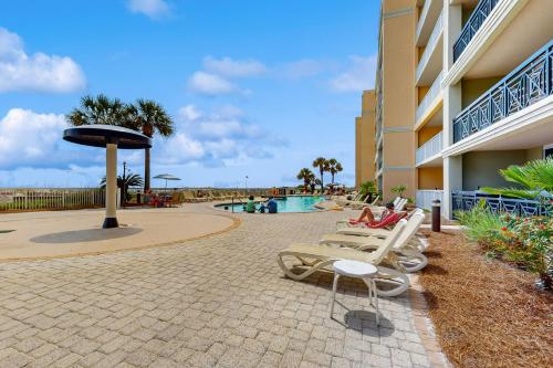 a group of lounge chairs next to a building at Roomy beachfront condo with full kitchen shared pool and beach access in Fort Walton Beach