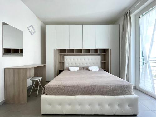 a white bedroom with a large bed and a desk at Relax Ligure in Boissano