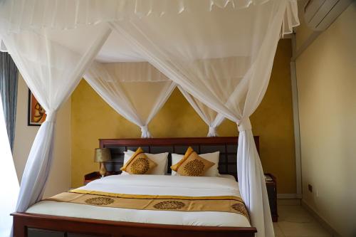a bedroom with a canopy bed with white curtains at Nican Resort Hotel Seguku Entebbe in Entebbe