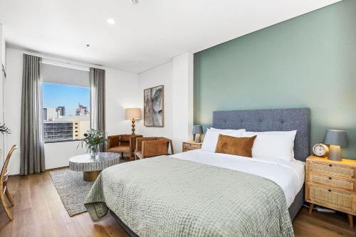 a bedroom with a large bed and a large window at Small Moments in Perth