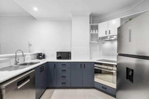 a kitchen with blue cabinets and a stainless steel refrigerator at River Fringe Urban Retreat in Perth