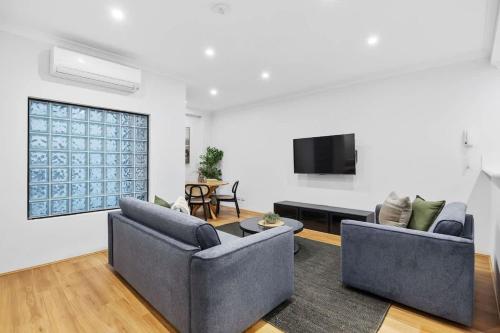 a living room with two couches and a flat screen tv at River Fringe Urban Retreat in Perth