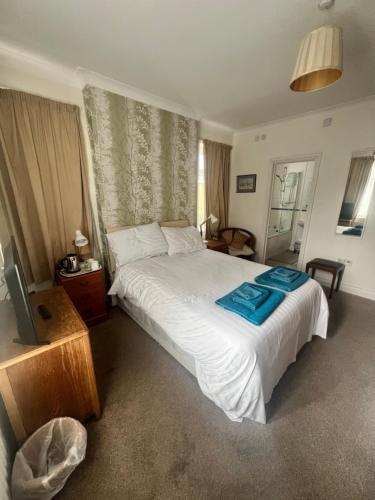 a bedroom with a large white bed and a television at Brantwood Guest House in Christchurch