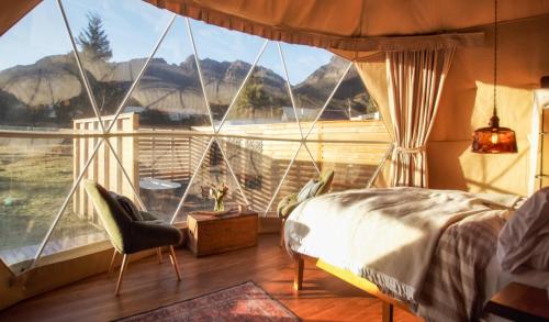 a bedroom with a large window with a bed and a chair at Wilder Tasmania in Gowrie Park