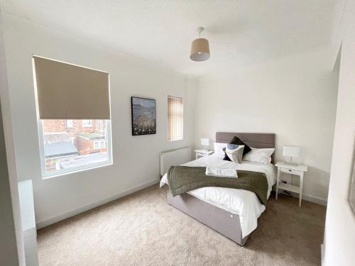 a white bedroom with a bed and a window at 3 Bed plus Sofa sleeps 6 central in Middlesbrough