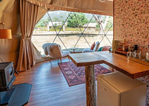 a living room with a table and a large window at Wilder Tasmania in Gowrie Park