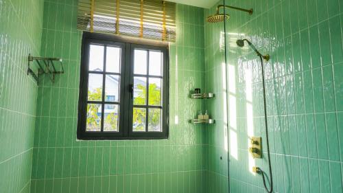 a green bathroom with a window and a shower at Bơ Home Novaworld in Phan Thiet