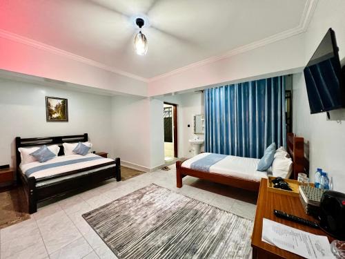 a hotel room with two beds and a television at Shanvilla Resort Ltd in Murangʼa