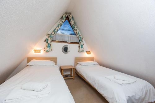 two beds in a attic room with a window at Chalet 11 in Deal