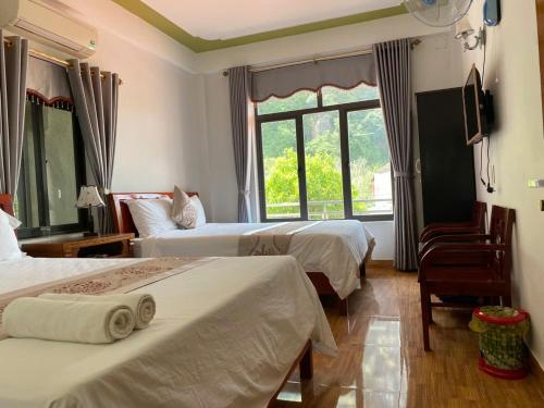 a hotel room with two beds and a window at Son Tinh Hotel in Phong Nha
