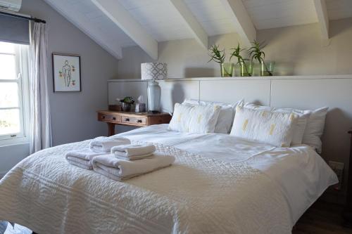 a bedroom with a white bed with towels on it at Kuruma Farm Cottages in Worcester