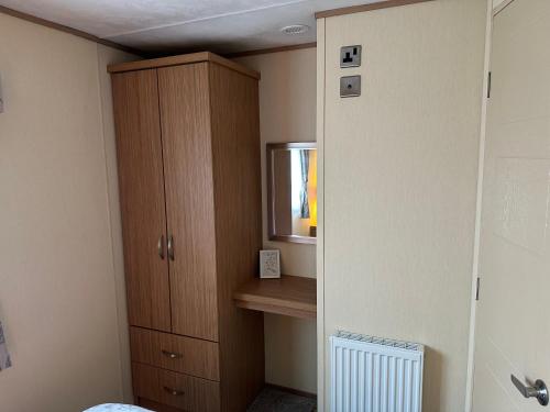 a bedroom with a cabinet and a television in it at The Cosy Hedgerow in Port Carlisle