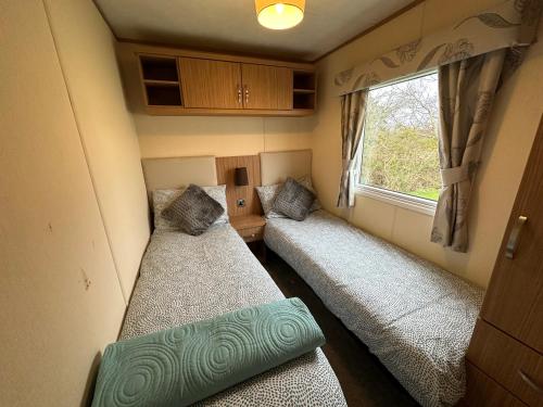 two beds in a small room with a window at The Cosy Hedgerow in Port Carlisle