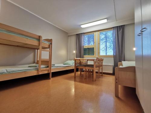 a bedroom with bunk beds and a table and chairs at RIEKKO Hostel in Kuusamo