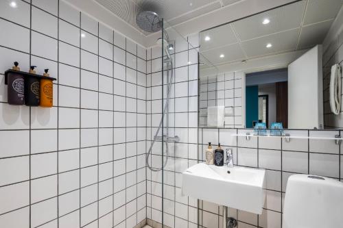 a white tiled bathroom with a sink and a mirror at Hotel Atlantic in Aarhus