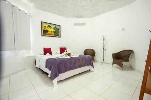 a white bedroom with a bed with red pillows at Pousada Marajoara- Hotel Fazenda-Turismo de Aventura in Soure