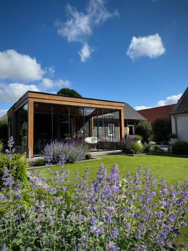 a house with a garden with purple flowers at B&B Logeren bij van Heeren in Made