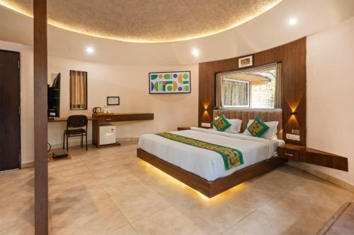 a bedroom with a bed and a desk in a room at Treebo Premium Mowgli's Den, Pench Tiger Reserve, Turia in Khawāsa