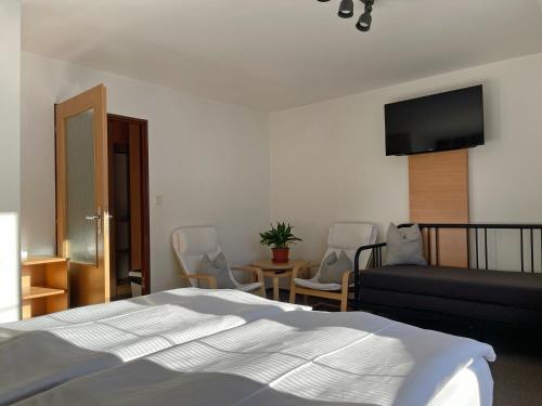 a bedroom with a bed and a couch and chairs at Penzion Praděd in Malá Morávka