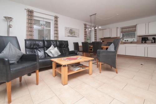 a living room with black leather furniture and a table at Ferienhaus Carpe Diem in Greetsiel